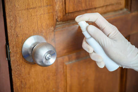 Shot of someone hand using alcohol hand sanitizer spraying on the door knob before open it. Hand sanitizer used to decrease infectious or kills germs, bacteria even more coronavirus.の写真素材