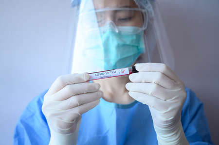 Nurse wearing scrubs and holding a sample test tube with blood for 2019-nCoV analyzing.