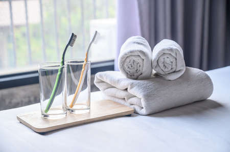 Set of hotel amenities (such as towels, drinking glass, toothbrush etc) on the bed. Hotel amenities is something of a premium nature provided in addition to the room when renting a room.の写真素材