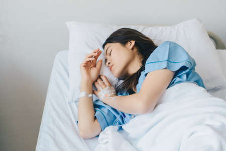 Portrait of sickness patient woman lying on hospital bed, resting for recovery. Conceptual of...