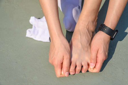 Cropped view of runner woman suffering from foot injury and she trying to do foot massage by herself. A foot massage used to decrease pain, relieve tension and improve circulation.の写真素材