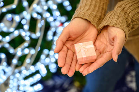 Cropped shot of someone hand with a small pink wrapped gift box. Gift or present is an item given to someone without the expectation of payment or anything in return.の写真素材
