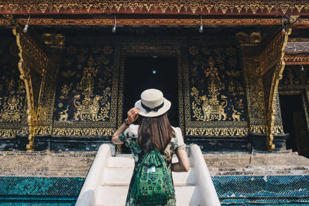 Back view of woman tourist visiting Wat Xieng Thong an iconic temple in Luang Prabangの写真素材