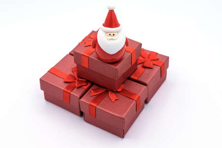 A Santa claus doll with a group of Christmas gift box isolated on white background. This dolls is...