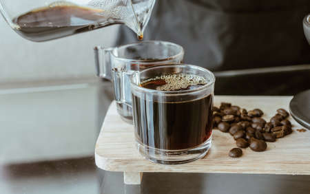 Cropped shot of Barista pouring a hot coffee after drip in a glass cup of coffee. Conceptual of how to making drip coffee by herself.の写真素材
