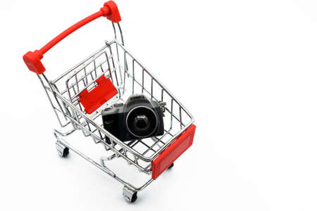 A shopping cart carrying toy camera isolated on white background. A cart is a vehicle designed for transport for carring something.の写真素材