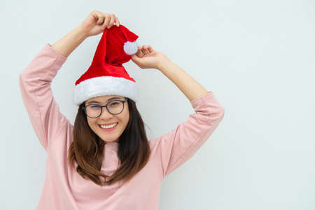 Portrait of happiness Asian woman wearing Santa hat and lean on the white wall background. Celebration of Christmas and New year festival concepts.の写真素材