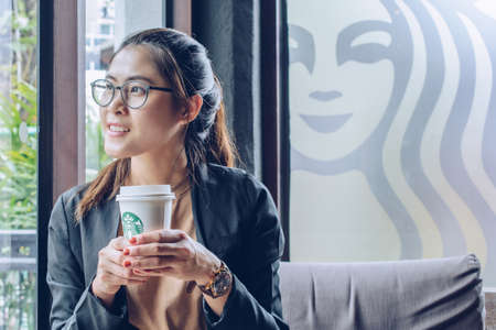 Chiang Mai, Thailand : May-15-2019 : Business Asian woman holding a cup of Starbucks coffee in Starbucks coffee shop.のeditorial素材