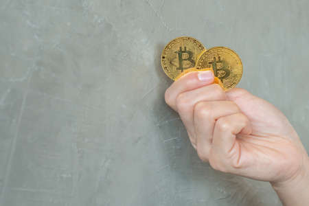 Close up of someone hand holding two pieces golden Bitcoin. Bitcoin is one of the popular...