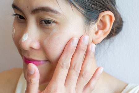 Close up of Asian woman marking and applying cream concealer on her facial skin. Concealer is a type of cosmetic that is used to mask dark circles, age spots, large pores etc.の写真素材