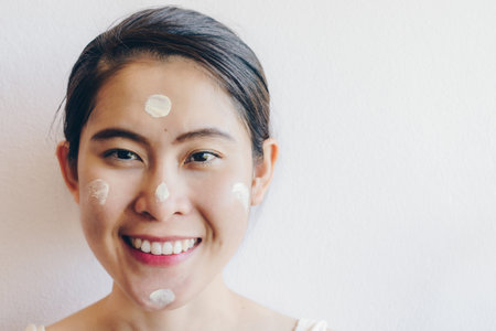 Portrait of Asian woman marking and applying cream concealer on her facial skin. Concealer is a type of cosmetic that is used to mask dark circles, age spots, large pores etc.の写真素材