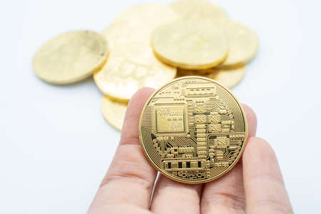 Close-up of someone hand holding golden Bitcoin isolated on white background. Bitcoin is one of the...