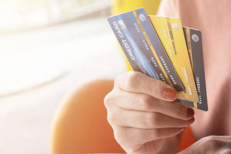 Cropped shot view of female hands holding her credit cards. Credit card lets cardholders borrow funds with which to pay for goods and services depend on the condition that cardholders pay back.の写真素材