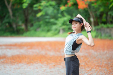 Portrait of runner woman doing stretching and warming up her body before running in the park. The benifit of stretching can increasing flexibility performance and reduce risk of injury.の写真素材