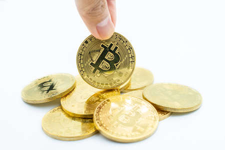 Someone finger with stack of golden Bitcoin isolated on white background. Bitcoin is one of the...