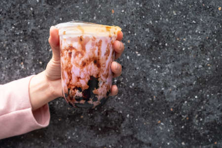 Cropped shot of someone hand holding a cup of iced Bubble milk tea mixed with Taro. Bubble tea was a traditional drink in Taiwan before it became hugely popular all over the world.の写真素材