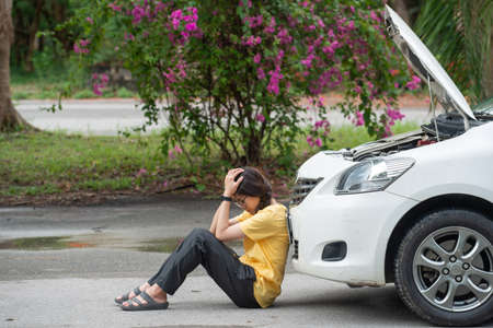 Young stressed woman having trouble with her car breakdown on the road and she waiting someone can...