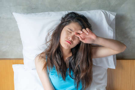 Portrait of young Asian woman feeling sleepy and tired after sleepless night. Shot of female hates...