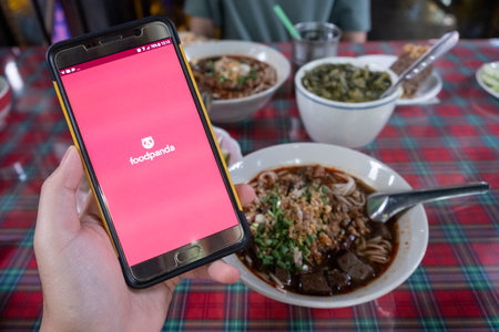 Chiang Rai, Thailand : 26-June-2019 : Someone hand holding smartphone and using Foodpanda application to order food from a variety of restaurants online.のeditorial素材
