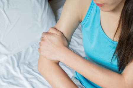 Close-up of woman holding her arm pain. Suffering painful caused by injury or overuse.