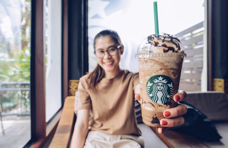Chiang Mai, Thailand : May-15-2019 : Asian woman holding a cup of Triple mocha frappuccino in Starbucks coffee shop. One of popular drinks menu of Starbucks coffee.のeditorial素材