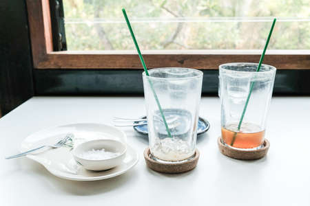 Group of empty glasses and empty plate on the table after finished meal. Various objects on the table in restaurant or cafe after customer has gone.の写真素材