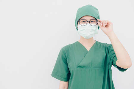 Portrait of young Asian nurse with surgeon uniform, wearing a surgical mask for protection from inhaling airborne bacteria or virus disease.の写真素材