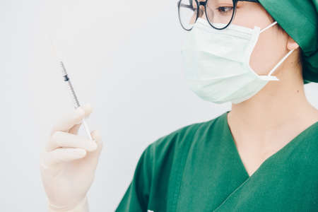 Close-up of young surgery nurse or doctor looking at a syringe needle preparation for injection. Conceptual shot of healthcare and medical concept.の写真素材