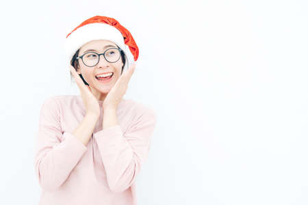 Portrait of happiness Asian woman wearing Santa hat and looking to isolated white wall copy space background. Celebration of Christmas and New year festival concepts.の写真素材