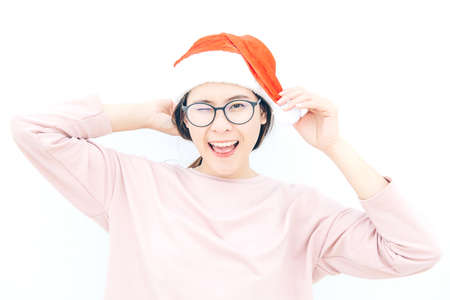 Portrait of Asian woman wearing Santa hat with isolated white wall background. Celebration of Christmas and New year festival concepts.の写真素材
