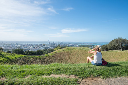 Tourist relaxing on Mount Eden crater and looking to Auckland the largest city in North island of New Zealand.の写真素材