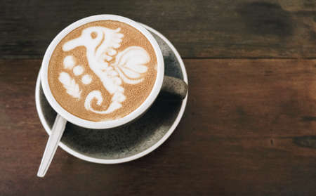 A cup of Latte/Cappuccino with a seahorse latte art on the water surface. Barista art design.の写真素材