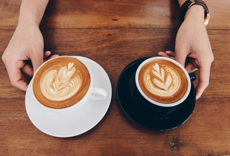 View of couple cup of hot latte coffee with hot cappuccino coffee serving on the wooden table.の写真素材