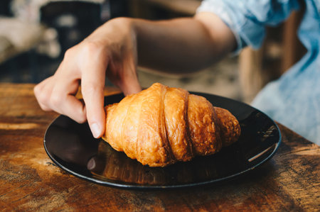 Cropped shot view of female hand catching croissant before eat.の写真素材