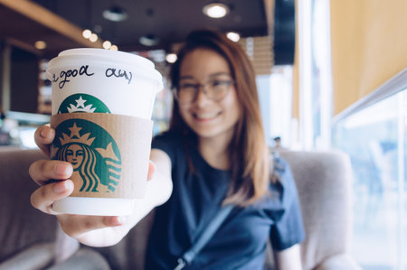 Chiang Rai, Thailand : May-23-2018 : Happy Asian girl showing a cup of Starbucks coffee in Starbucks coffee store.のeditorial素材