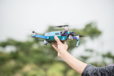 Cropped shot view of human holding a flying drone in his hand.の写真素材