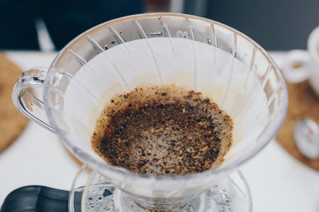 Close up of coffee drip filter after Barista pouring hot water on ground coffee. Drip coffee is made by pouring boiling water over ground coffee (the grind of which being much coarの写真素材
