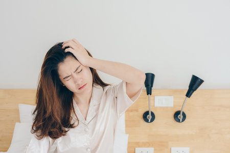 Portrait of asian woman feel headache after she wake up in the early morning.の写真素材