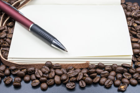 A book open the empty page on the roasted coffee beans with isolated black background.の写真素材