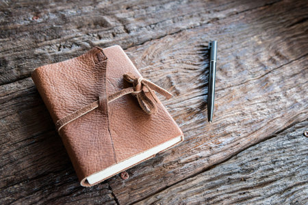 The leather book and pen on the wood table. A notebook is a small book for writing notes in.の写真素材