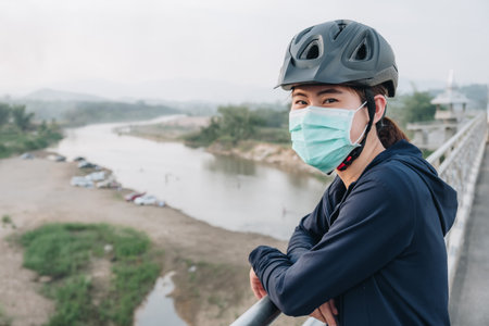 Portrait of young woman wearing a mask while riding a bicycle outdoor for protect and prevent the spread of virus. Conceptual of new normal lifestyle, everybody should wearing a maの写真素材