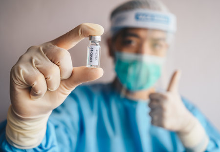 Scientist doctor holding a sample test bottle of Covid-19 vaccine and showing thumb up. Vaccination is one of the most effective ways to prevent diseases and helps the bodyâs immunの写真素材