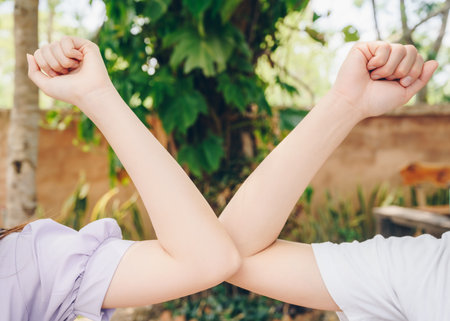 Cropped shot of two women bump elbows for greeting during coronavirus epidemic. The elbow bump was suggested as an alternative way for reduce your risk of spreading or contractingの写真素材