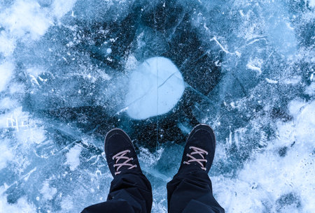 A foot of tourist standing on the cracks surface of frozen lake Baikal in the winter season of Siberia, Russia. Lake Baikal is the largest freshwater lake in the world and the worlの写真素材