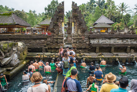 Bali, Indonesia : 14 July 2018 : Group of tourist interesting and waiting queue for taking a bath in Pura Tirta Empul the holy spring water temple in Bali, Indonesia.のeditorial素材