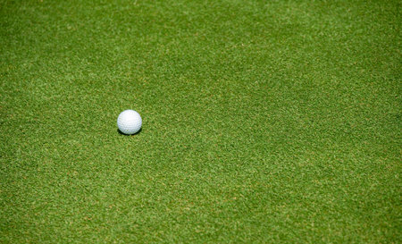 A golf ball on the green in golf course. The green is a special area of grass on the golf course that surrounds each hole.の写真素材