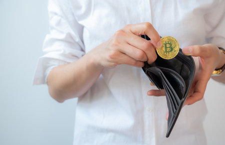 Cropped shot of woman collecting golden Bitcoin token in leather wallet. Bitcoin is one of the popular cryptocurrency, a virtual currency or a digital currency.の写真素材