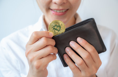 Happiness woman holding leather wallet with a golden Bitcoin token in her hands. Bitcoin is one of...