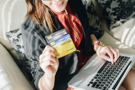 Close up of business woman holding credit card during using laptop for online shopping. Online shopping is the process of buying goods and services from merchants over the Internetの写真素材