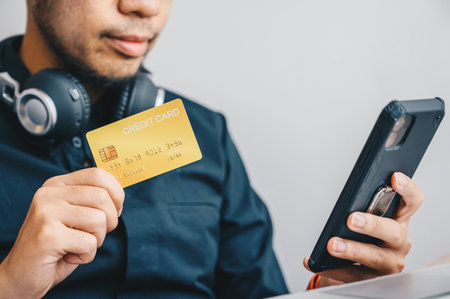 Close-up of businessman holding gold credit card for payment online shopping on smartphone. Credit...